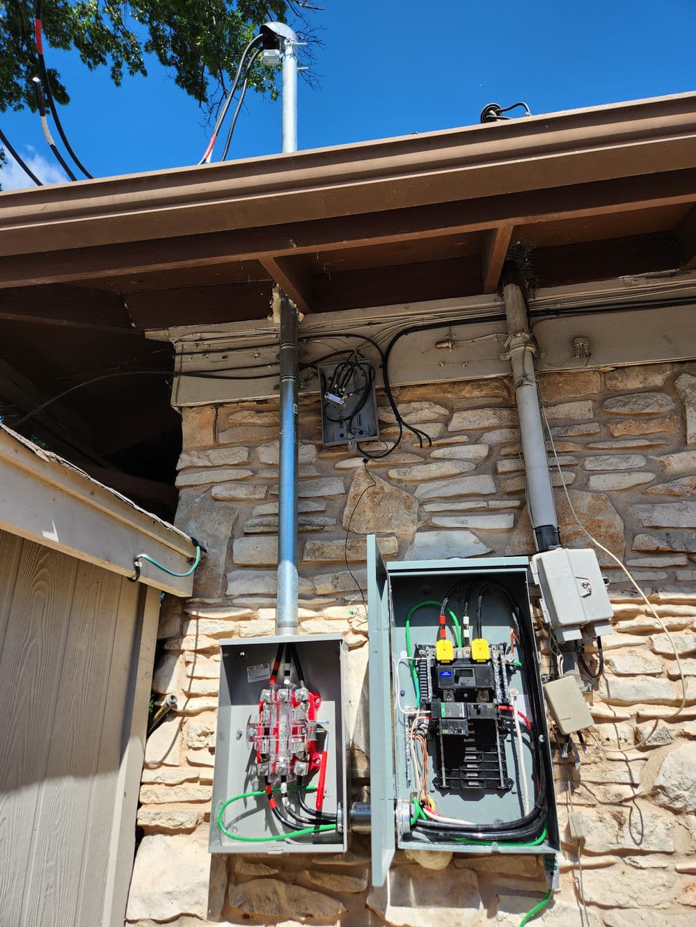 Electrical installation on a stone wall with circuit breakers and wiring visible.