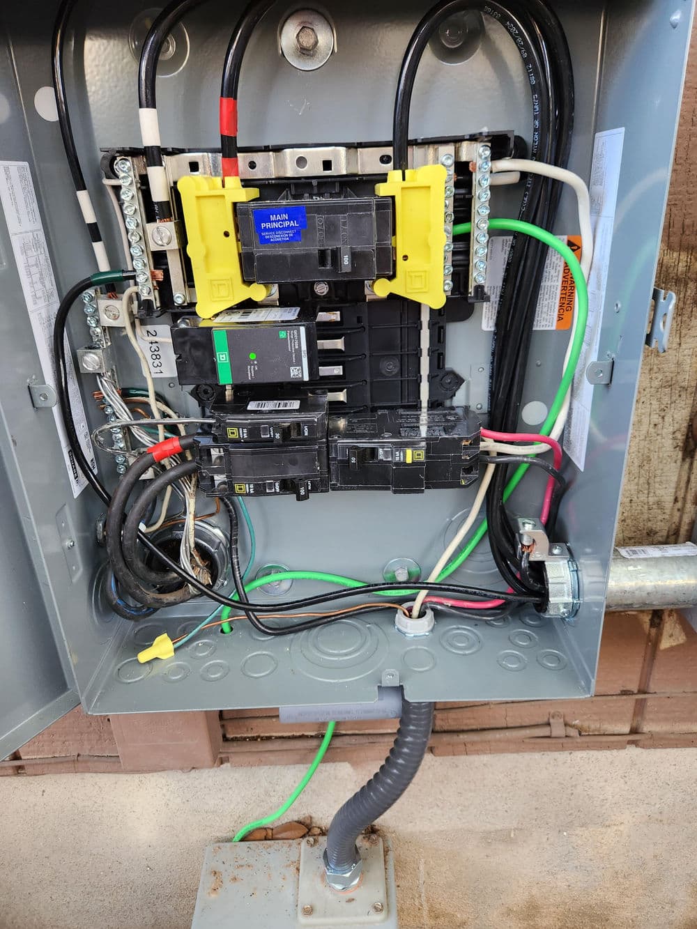 Electrical panel with circuit breakers and wiring, showcasing connections and safety labels.