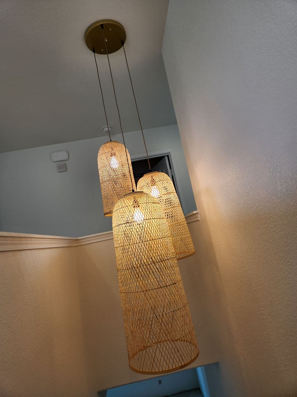 Modern pendant lights in a stylish woven design illuminate a staircase.