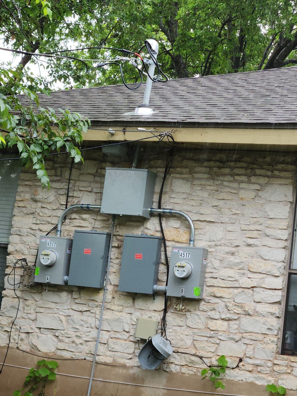 Utility meter setup on a stone wall, featuring multiple electric meters and monitoring equipment.
