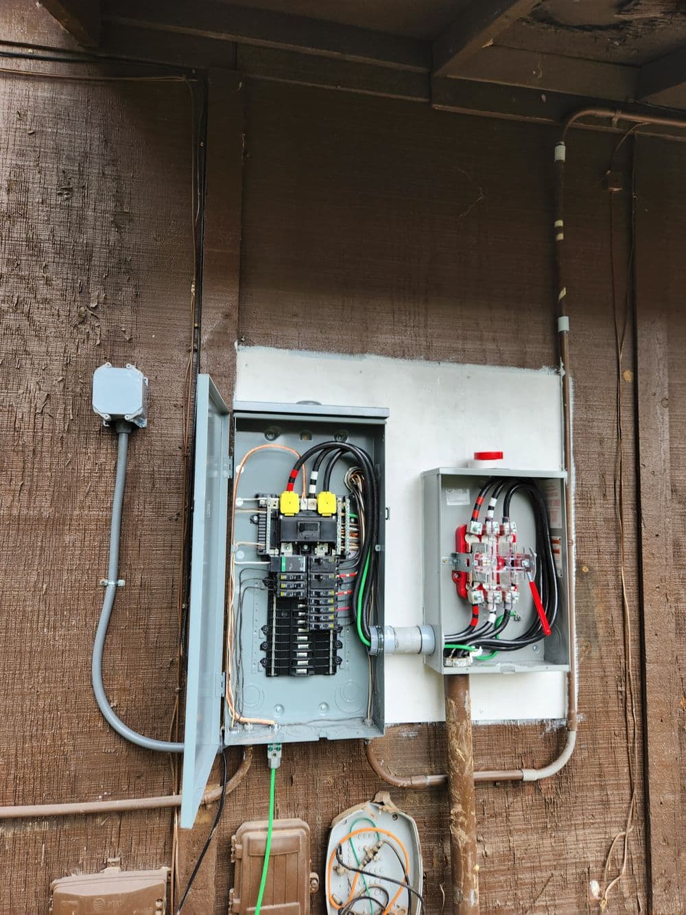 Electrical panels and circuit breakers mounted on a wall, featuring cables and connections.