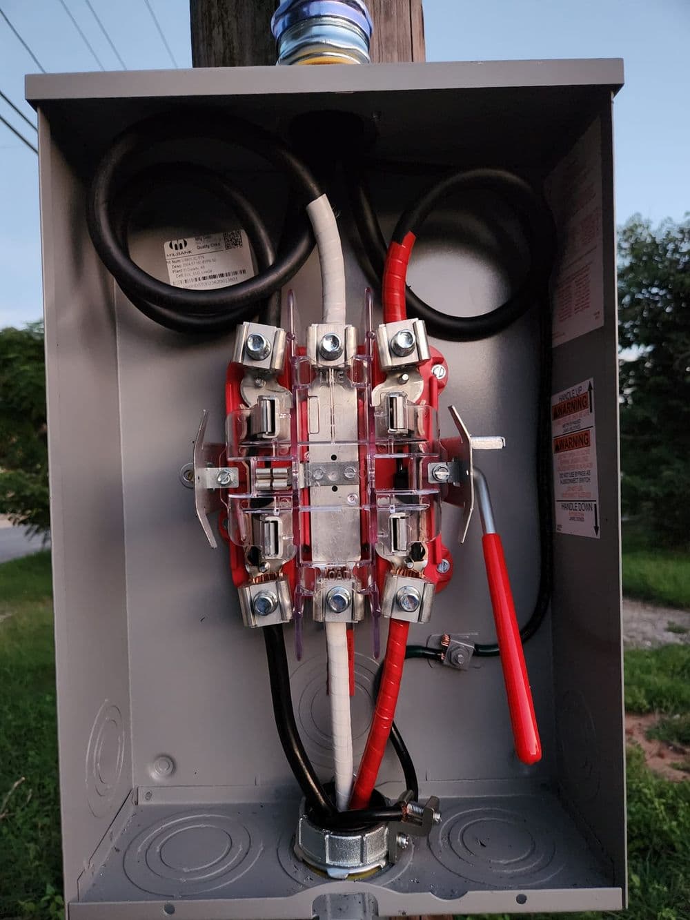 Electrical junction box mounted on a utility pole with various cables and connectors.