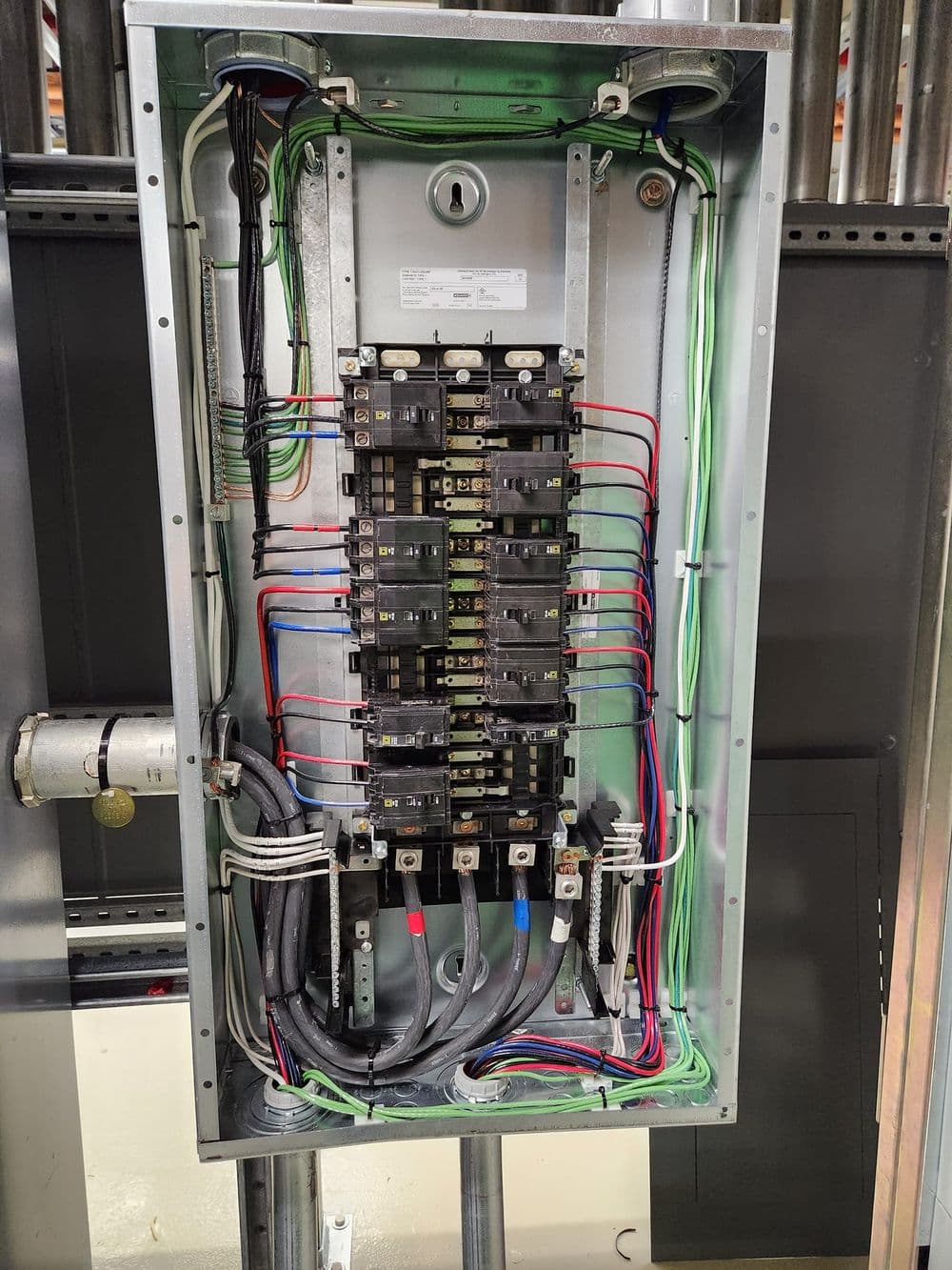 Electrical panel with circuit breakers and wiring, showcasing a detailed interior layout.